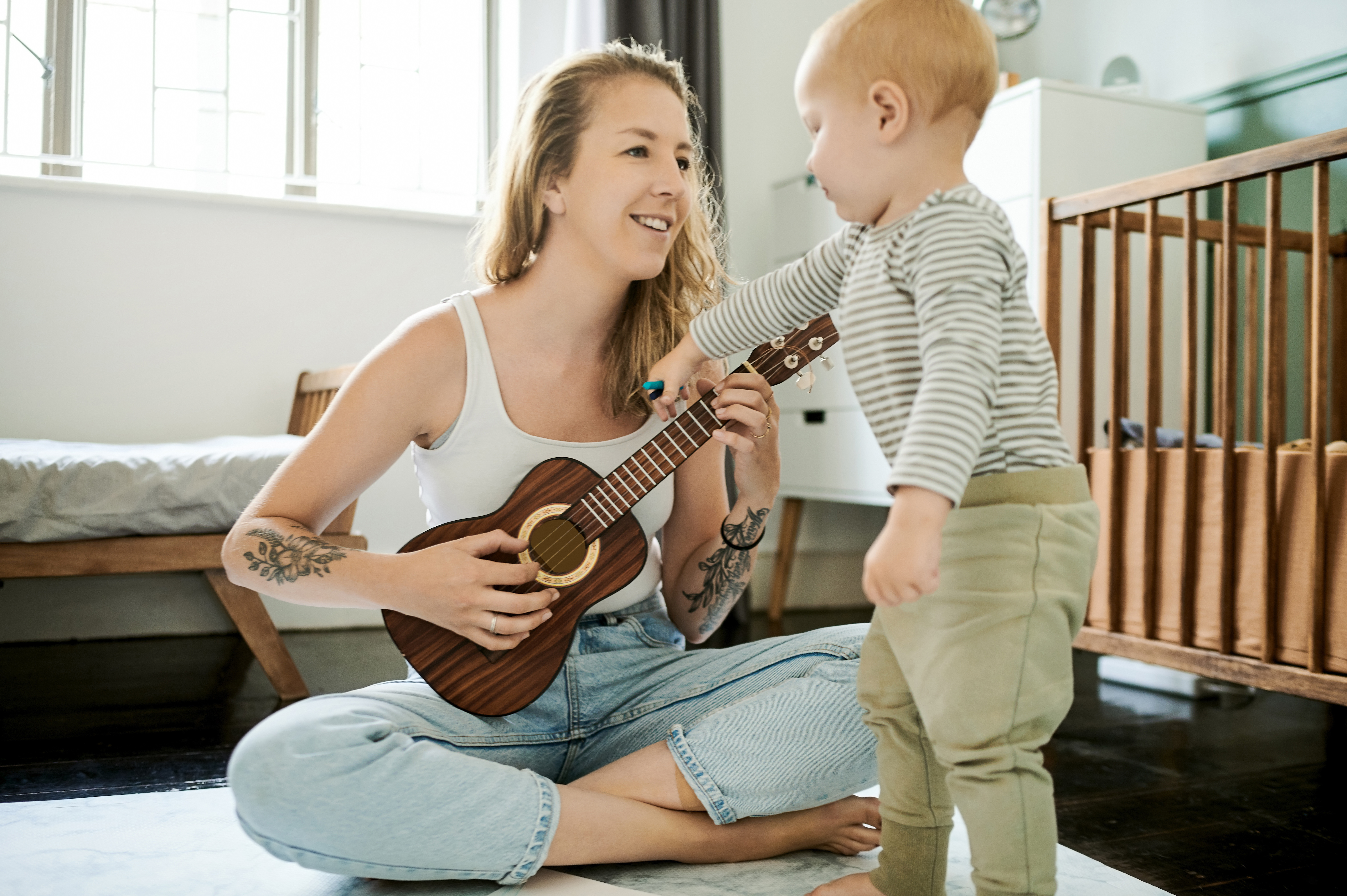 parent playing ukulele and singing with toddler