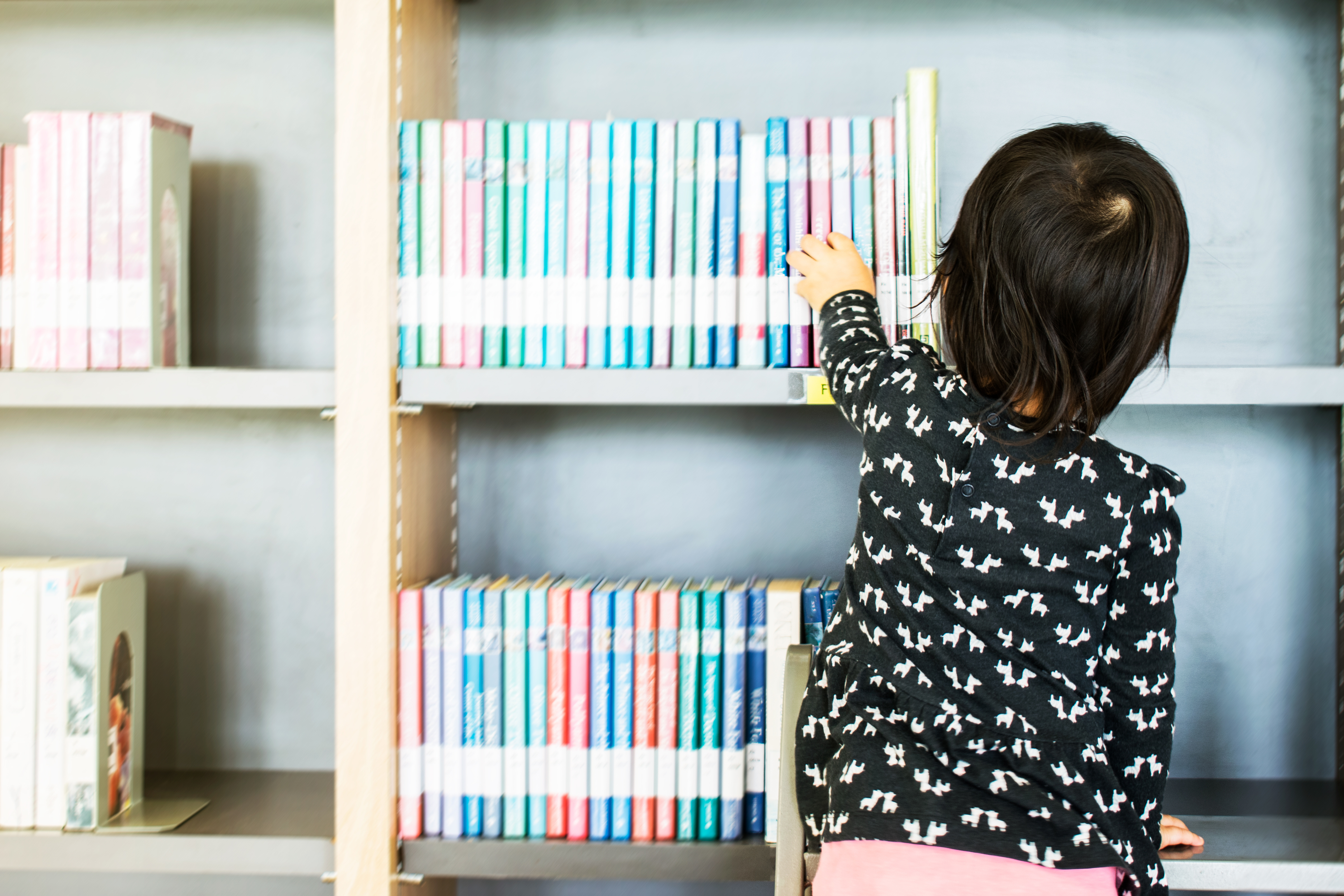 image of a young child picking out a book from the shelf