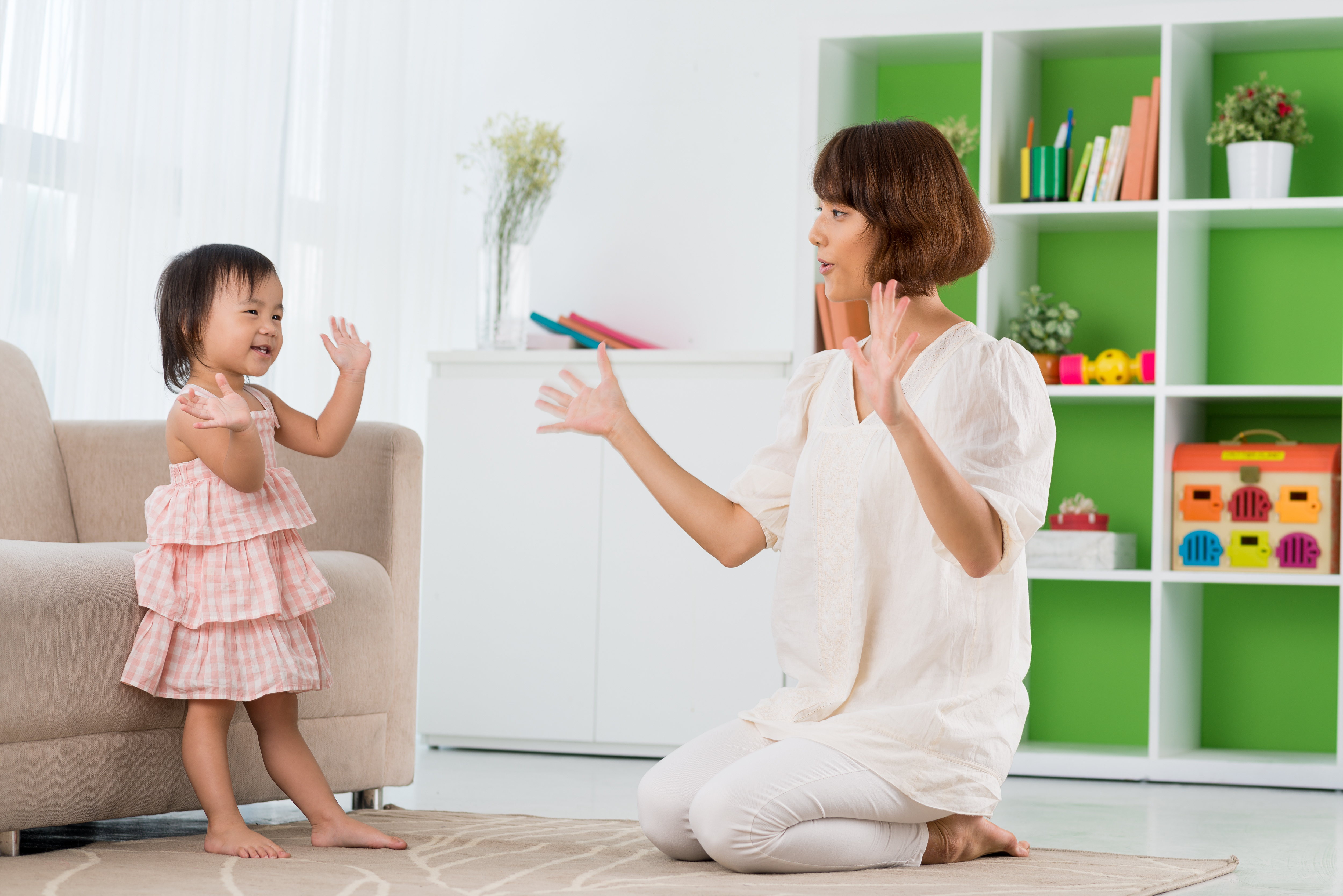 image of a parent and child playing a clapping game on the floor