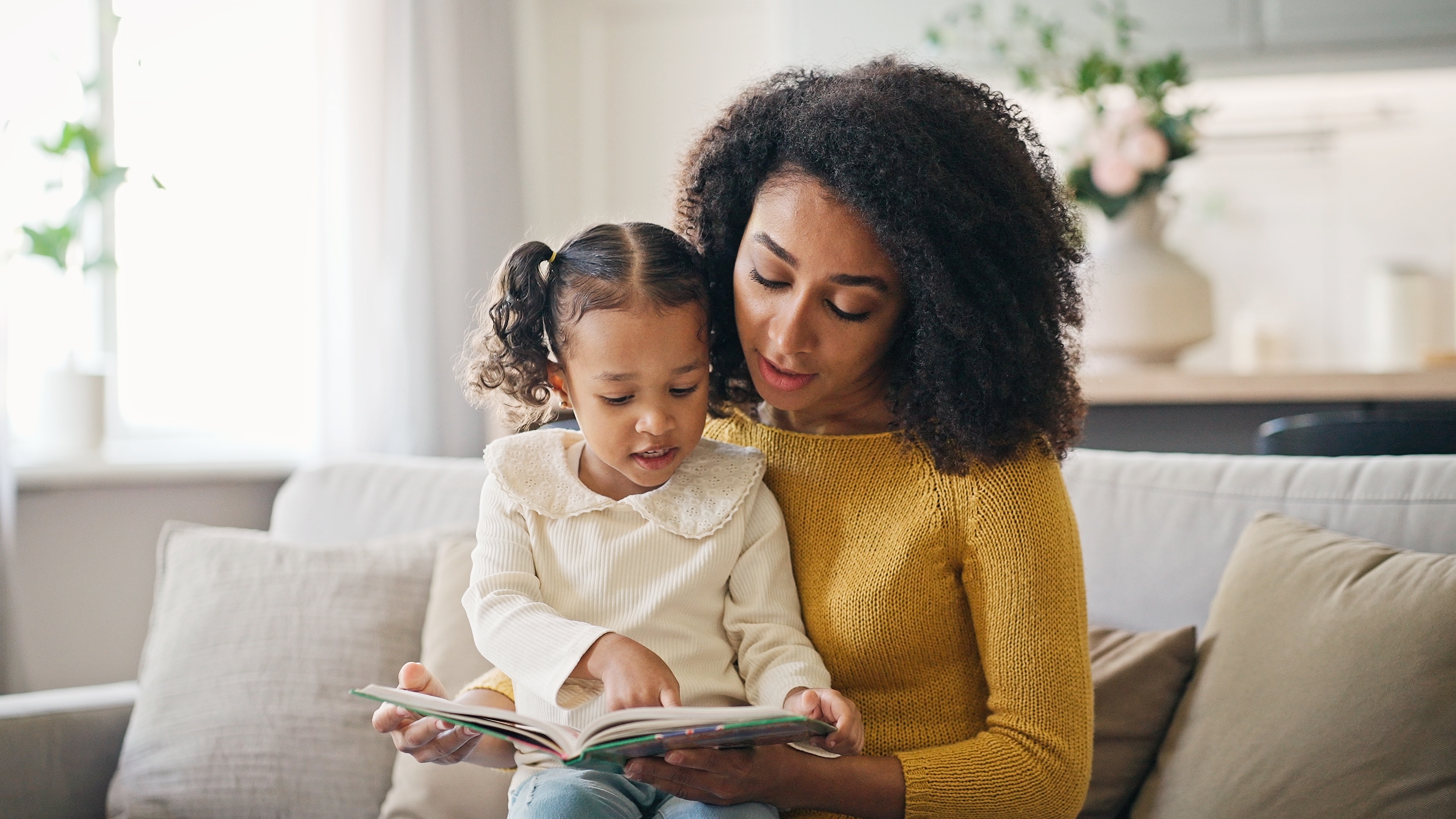image of a mother and daughter reading together on the couch