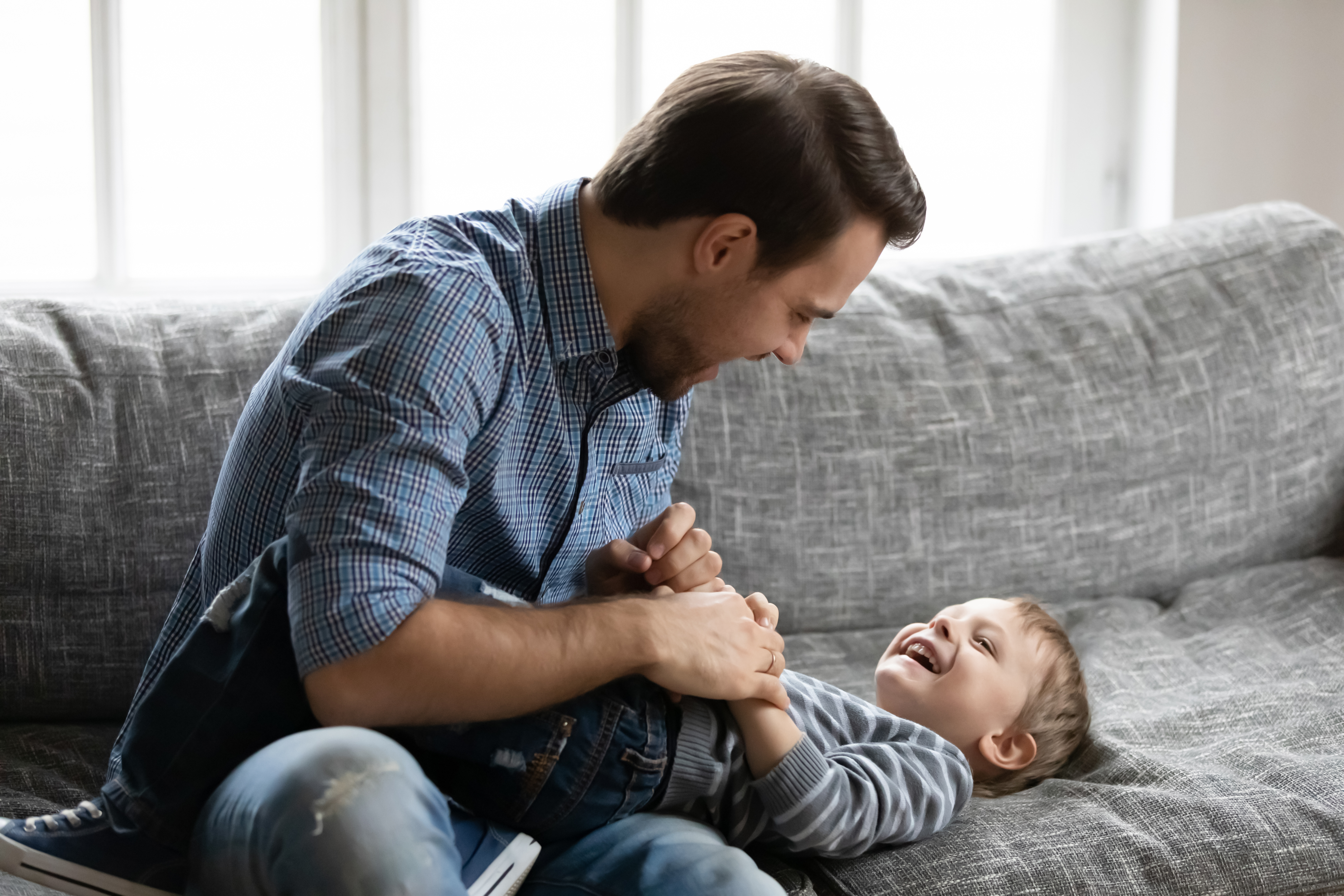 image of a parent and child playing a tickle game on the couch
